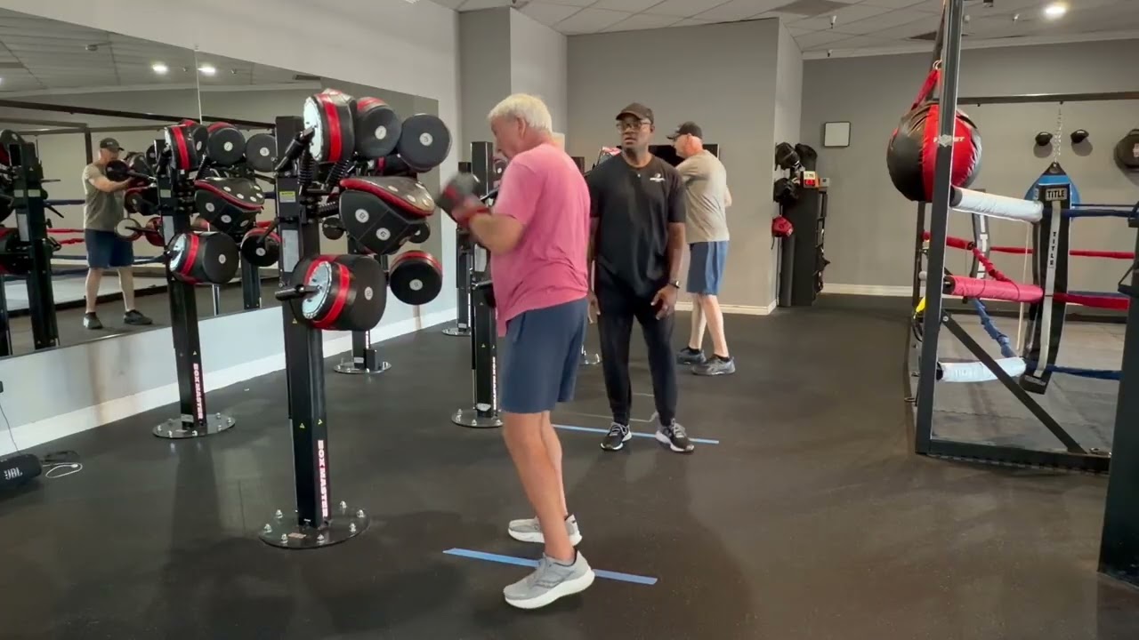 A participant practices boxing movements with a Parkinson’s 101 coach in the gym
